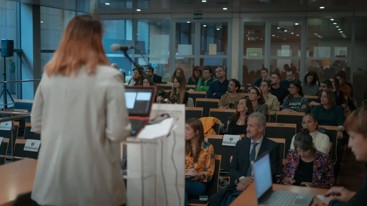 Imagen de una chica dando una charla delante de otras personas en una sala